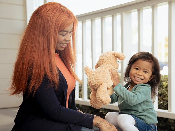 Young mother playing with daughter on porch