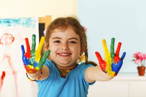 Smiling child holding up colorful painted palms
